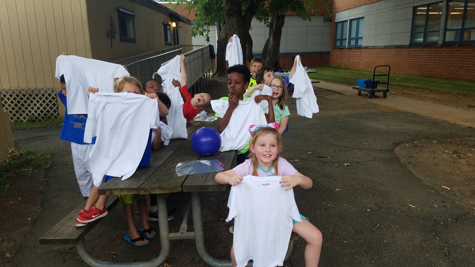 Kids holding up white t-shirts before tie-dye
